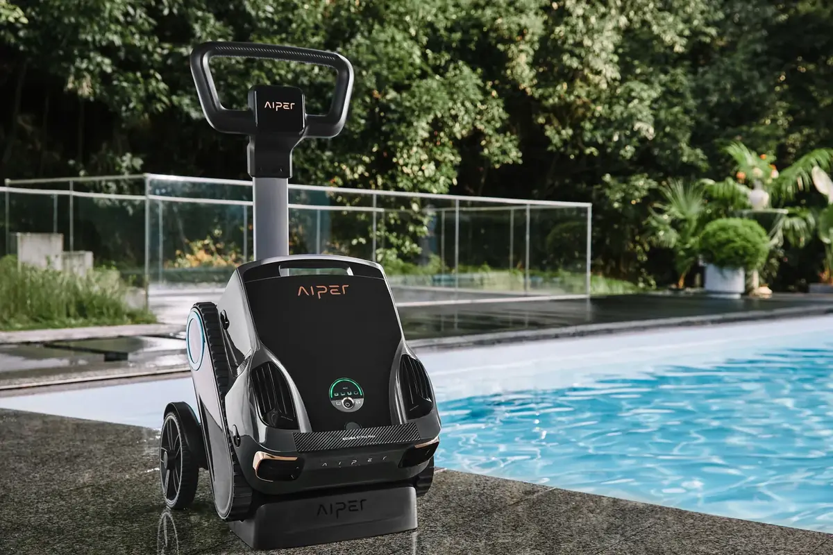 Aiper Scuba X1 Pro Max on its wheeled caddy and wireless charging dock beside a pool