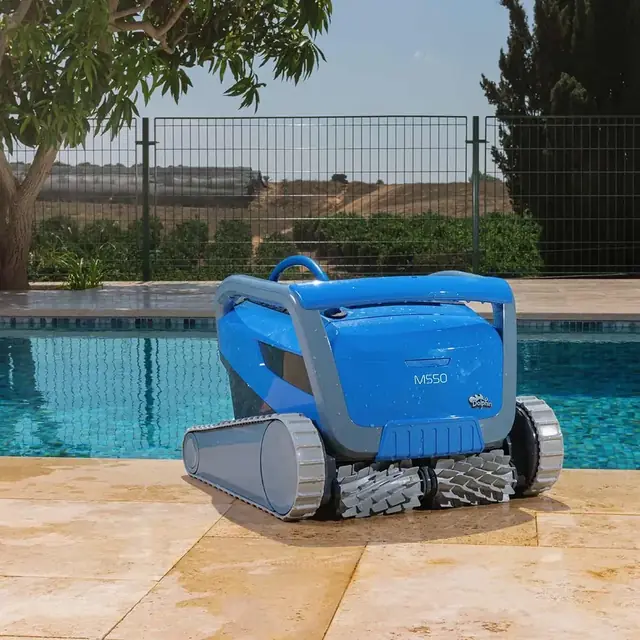 Dolphin M550 robotic pool cleaner sitting on a sandstone deck at the edge of an outdoor pool